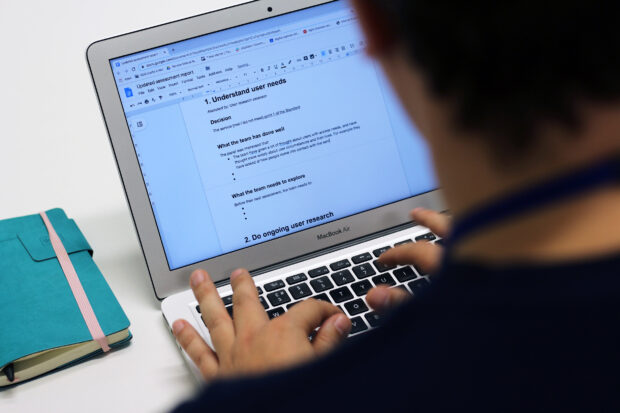 A person writing a service assessment report on their laptop; the top headline says: understand user needs