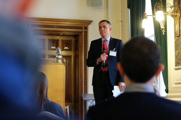 Dr Peter Bishop standing on stage after a talk listening to a question of a member of the audience, holding a microphone