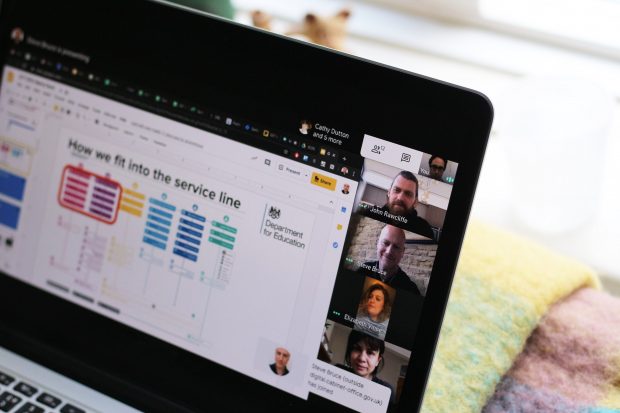 A laptop screen showing a remote service assessment taking place via video conference software with various people dialled in looking at a shared presentation headlined ‘How we fit into the service line’