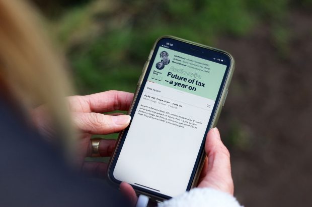 A person holding a phone showing an audio-only session on the future of tax, created by members of HMRC’s innovation team