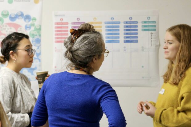 Three women standing in front of a wall with service maps