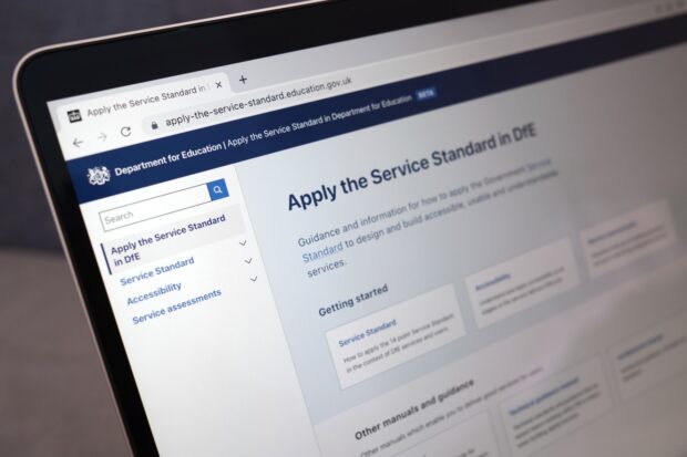 A photo of a laptop with a web browser opened, showing a page titled 'Apply the Service Standard in DfE'