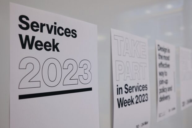 3 posters on a wall. One says Services Week 2023, the next Take part in Services Week 2023, the other is blurred text.