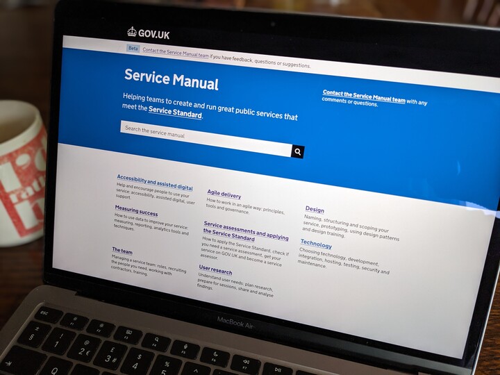 The Service Manual on GOV.UK is shown on a laptop screen, next to a cup of drink.